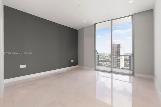 empty room with expansive windows and light tile patterned flooring