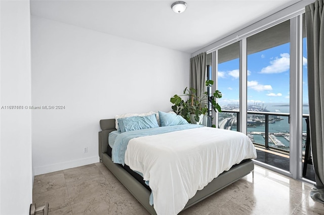 bedroom featuring access to exterior, a water view, and expansive windows