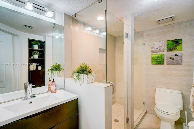 bathroom with walk in shower, vanity, a textured ceiling, tile walls, and toilet