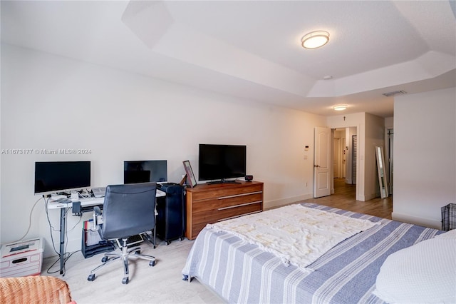 bedroom featuring light wood-type flooring and a tray ceiling