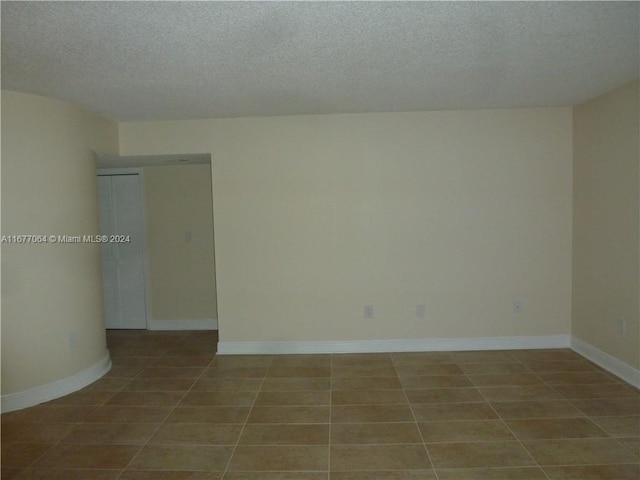 tiled empty room with a textured ceiling