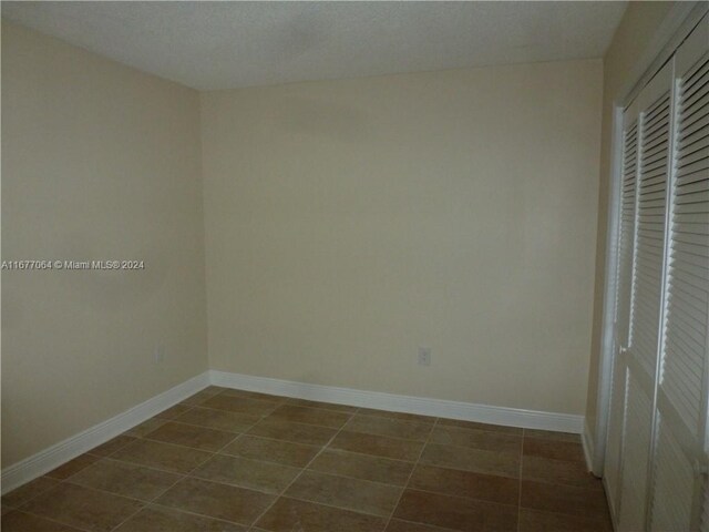 tiled empty room featuring a textured ceiling