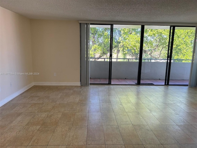 tiled empty room with a wall of windows and a textured ceiling