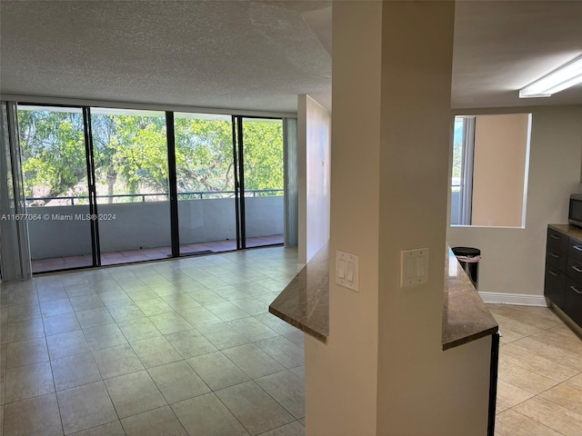 tiled spare room featuring a textured ceiling, floor to ceiling windows, and a wealth of natural light