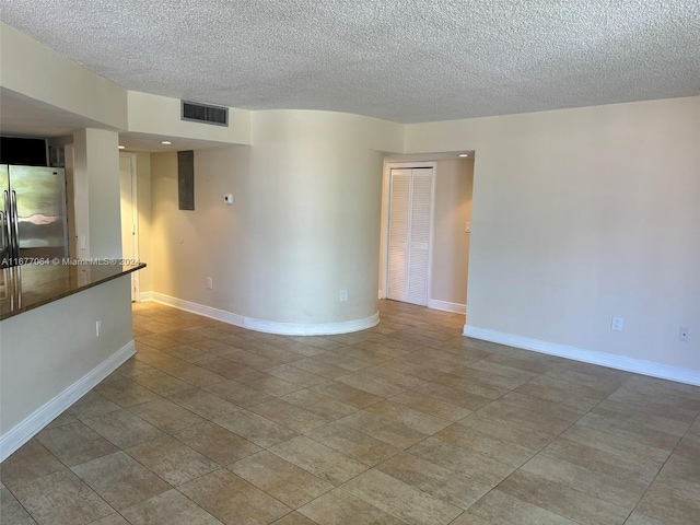 tiled empty room featuring a textured ceiling