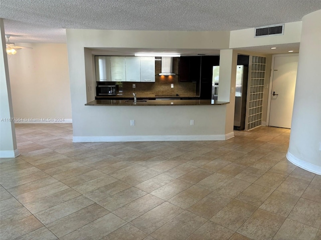 unfurnished living room featuring a textured ceiling, sink, light tile patterned floors, and ceiling fan