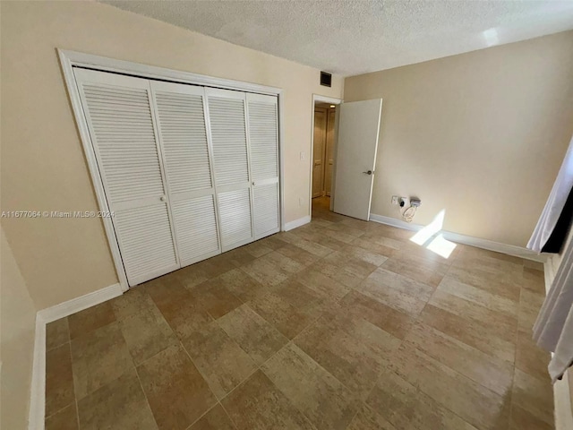 unfurnished bedroom featuring a textured ceiling and a closet