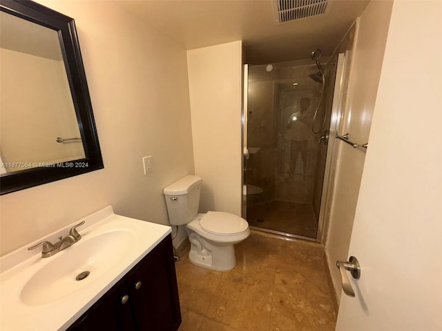 bathroom with vanity, a shower with shower door, and toilet