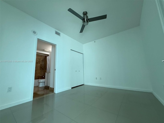 unfurnished bedroom featuring tile patterned flooring, ensuite bath, a closet, and ceiling fan