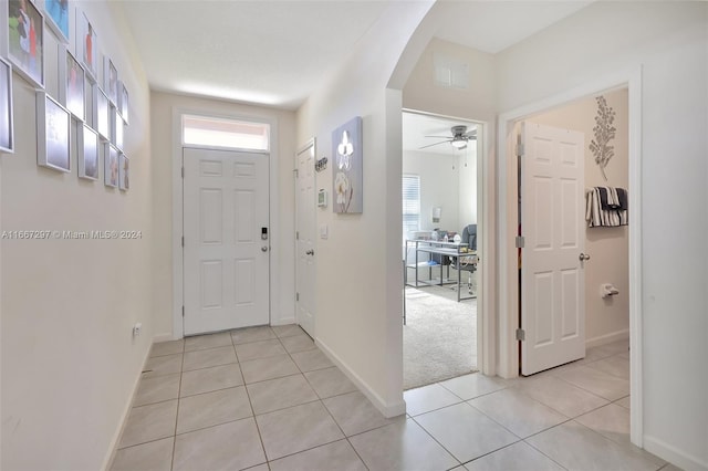 foyer entrance featuring light carpet, ceiling fan, and a wealth of natural light