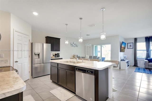 kitchen featuring dark brown cabinets, a center island with sink, sink, decorative light fixtures, and appliances with stainless steel finishes