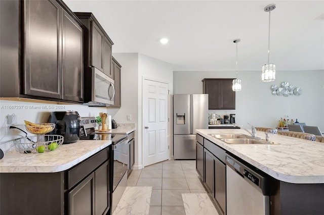 kitchen with appliances with stainless steel finishes, sink, hanging light fixtures, dark brown cabinetry, and a center island with sink