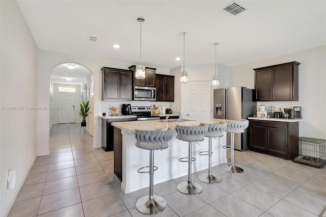 729 SW Lakehurst Dr, Port St Lucie, FL 34983 - kitchen featuring stainless steel appliances, a breakfast bar, dark brown cabinetry, light tile patterned floors, and a sink