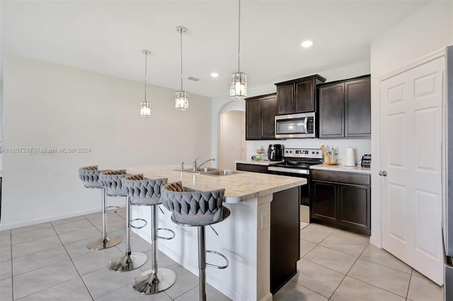 kitchen featuring a center island with sink, appliances with stainless steel finishes, a kitchen breakfast bar, pendant lighting, and sink