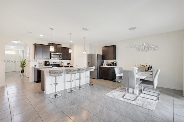 kitchen featuring a kitchen bar, a kitchen island with sink, decorative light fixtures, and stainless steel appliances