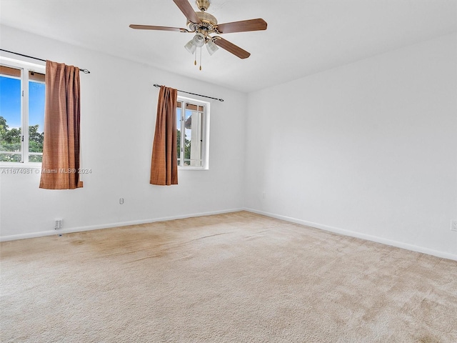 spare room with plenty of natural light, light carpet, and ceiling fan