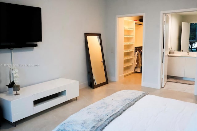 bedroom featuring a closet, ensuite bath, sink, and a walk in closet