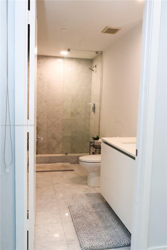 bathroom with vanity, toilet, and tiled shower