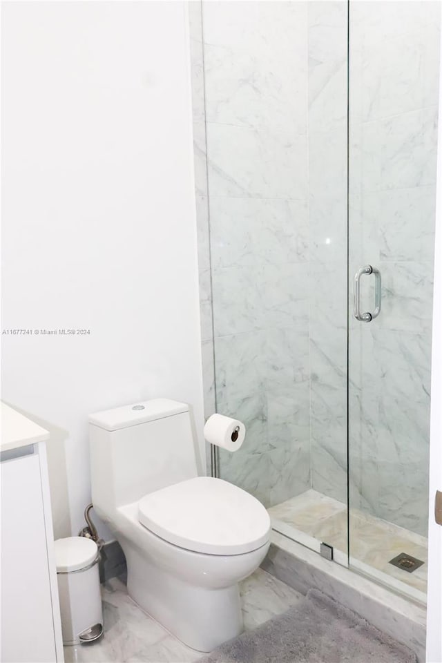 bathroom featuring toilet, vanity, and a shower with door