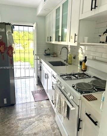 kitchen with white cabinetry, stainless steel refrigerator, white range with gas cooktop, and sink