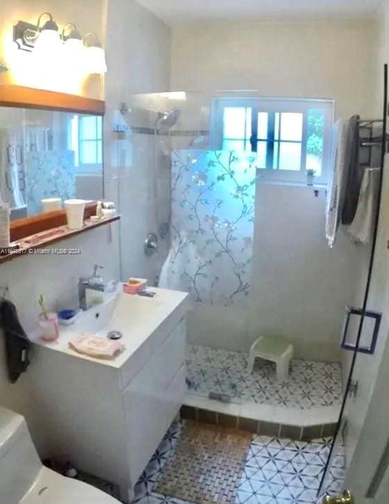 bathroom with vanity, toilet, a shower with shower door, and plenty of natural light