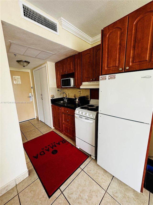 kitchen featuring crown molding, a textured ceiling, light tile patterned floors, and white appliances