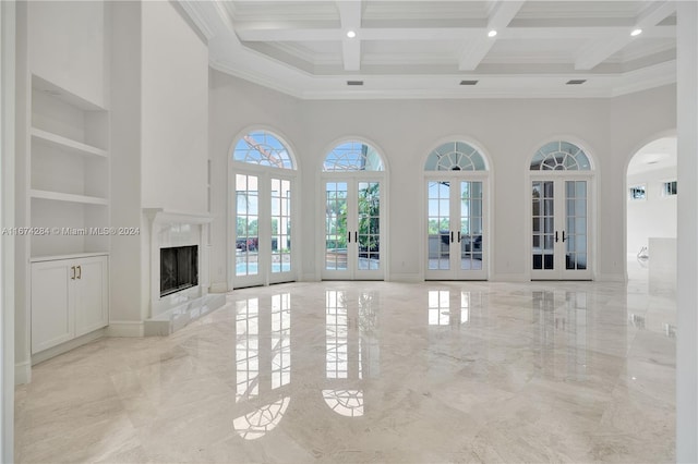 unfurnished living room with french doors, crown molding, and a high ceiling