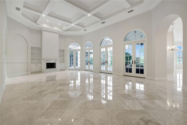 unfurnished living room with coffered ceiling, a towering ceiling, a wealth of natural light, and french doors