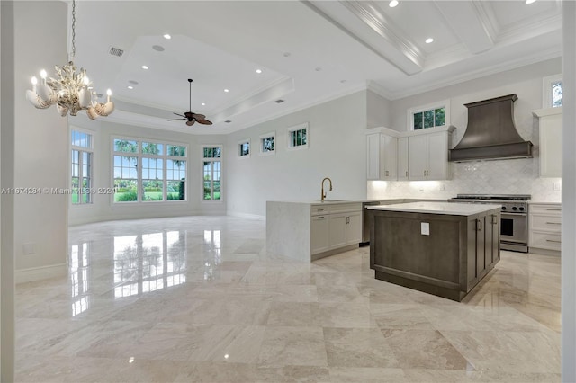 kitchen with white cabinetry, premium range hood, crown molding, high end stainless steel range, and ceiling fan with notable chandelier