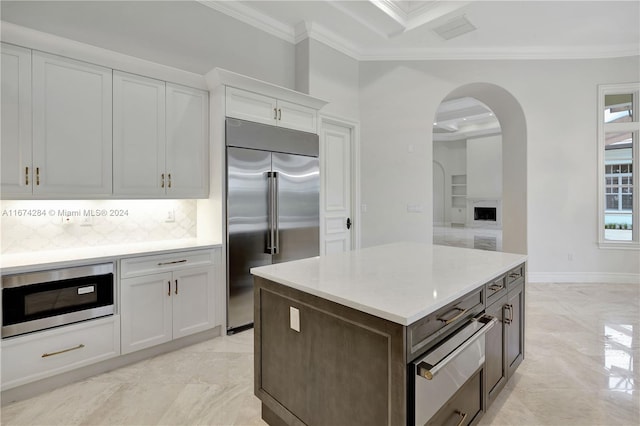 kitchen with decorative backsplash, appliances with stainless steel finishes, crown molding, beam ceiling, and white cabinets