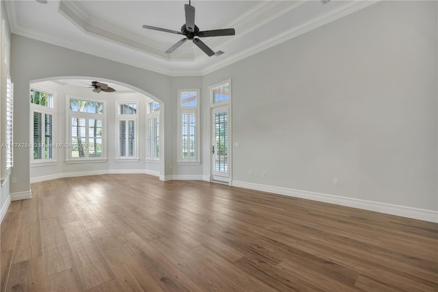 unfurnished room with hardwood / wood-style flooring, ceiling fan, crown molding, and a tray ceiling