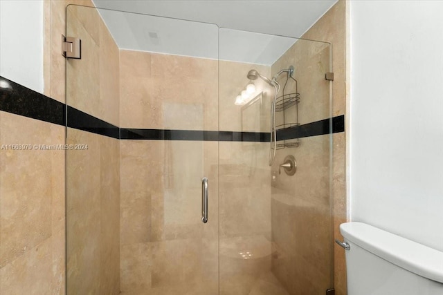 bathroom featuring toilet and a shower with door