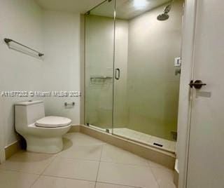 bathroom featuring toilet, a shower with shower door, and tile patterned flooring