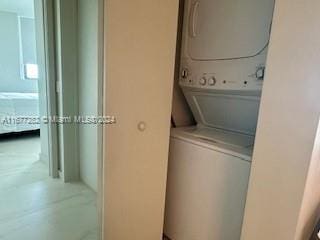 clothes washing area featuring stacked washing maching and dryer