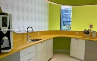 kitchen with white cabinetry, light tile patterned floors, and sink