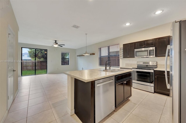 kitchen with ceiling fan, sink, dark brown cabinetry, an island with sink, and stainless steel appliances