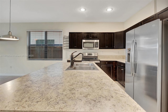 kitchen with stainless steel appliances, dark brown cabinets, decorative light fixtures, and sink