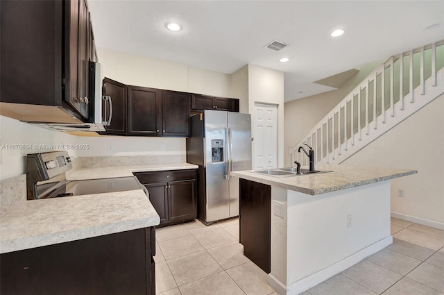 kitchen with sink, light tile patterned floors, stainless steel appliances, and an island with sink