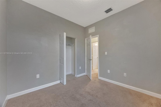 unfurnished bedroom with light carpet, a closet, and a textured ceiling