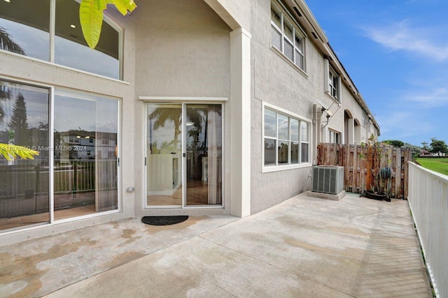 view of exterior entry with a patio area and central AC