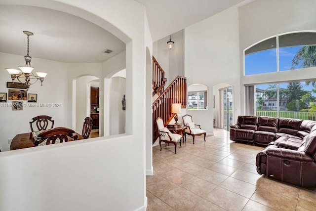 living room featuring a towering ceiling, a chandelier, and light tile patterned floors