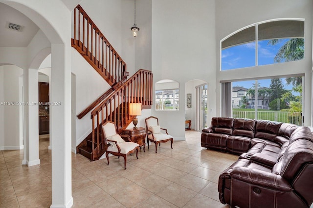 tiled living room featuring a towering ceiling and a wealth of natural light