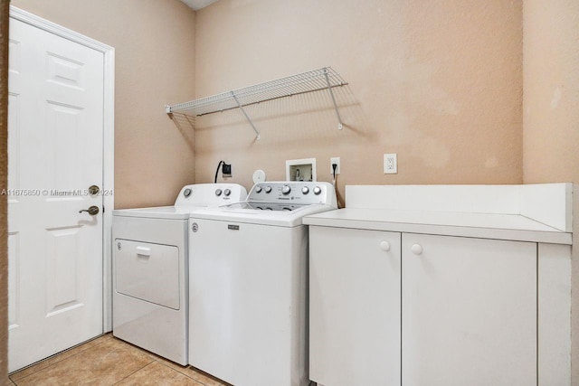 washroom featuring washer and dryer, cabinets, and light tile patterned floors