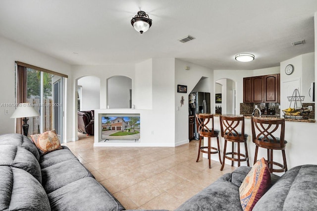 living room featuring sink and light tile patterned floors