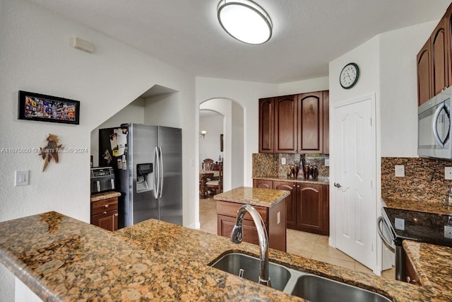 kitchen featuring stone counters, decorative backsplash, stainless steel appliances, and sink