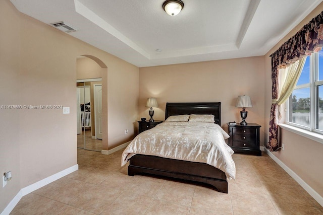 bedroom with light tile patterned floors and a raised ceiling