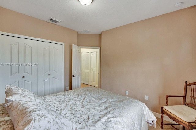 bedroom with a textured ceiling, carpet flooring, and a closet