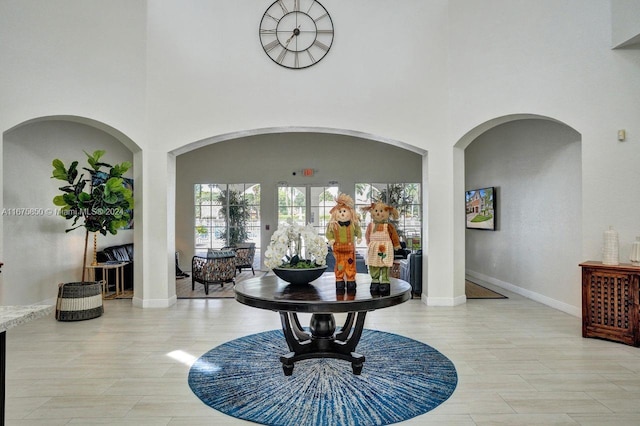 corridor featuring a towering ceiling and light hardwood / wood-style flooring