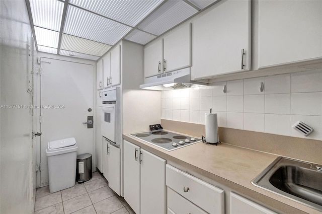 kitchen with white appliances, sink, backsplash, white cabinetry, and light tile patterned floors