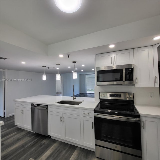 kitchen with appliances with stainless steel finishes, sink, kitchen peninsula, and white cabinets